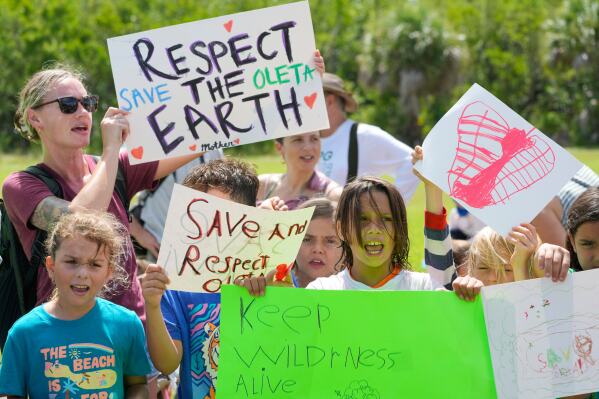 Protesters chant against Gov. Ron DeSantis' plan to develop state parks with business ventures such as golf courses, pickleball courts and large hotels, during a demonstration at Oleta River State Park, Tuesday, Aug. 27, 2024, in North Miami Beach, Fla. (AP Photo/Wilfredo Lee, File)