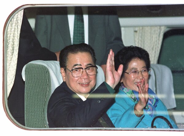 CORRECTS AGE TO 90, INSTEAD OF 91 - FILE - In this Nov. 13, 1997, file photo, then Chinese Premier Li Peng, left, and his wife Zhu Lin wave from a bullet train window before they leave for Odawara City, west of Tokyo, at the Tokyo Central station. Li Peng, a former hard-line Chinese premier best known for announcing martial law during the 1989 Tiananmen Square pro-democracy protests, has died. He was 90. (AP Photo/Shizuo Kambayashi, File)