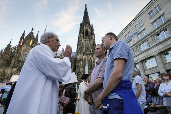 Same-sex couples take part in a public blessing ceremony in front of the Cologne Cathedral in Cologne, Germany, Wednesday, Sept. 20, 2023. Several Catholic priests held a ceremony blessing same-sex and also re-married couples outside Cologne Cathedral in a protest against the city's conservative archbishop, Cardinal Rainer Maria Woelki. (AP Photo/Martin Meissner)