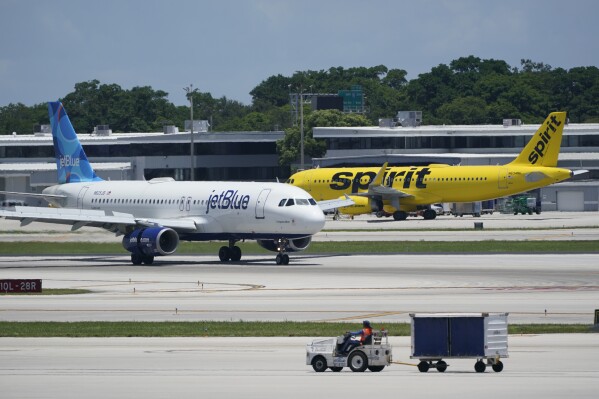 FILE - A JetBlue Airways Airbus A320, left, passes a Spirit Airlines Airbus A320 as it taxis on the runway, July 7, 2022, at the Fort Lauderdale-Hollywood International Airport in Fort Lauderdale, Fla. JetBlue Airways is making another move to try to save its proposed purchase of Spirit Airlines. JetBlue said Monday, Sept. 11, 2023 it reached a deal to turn over Spirit's gates at airports in Boston and Newark, New Jersey, to low-cost carrier Allegiant. (AP Photo/Wilfredo Lee, File)