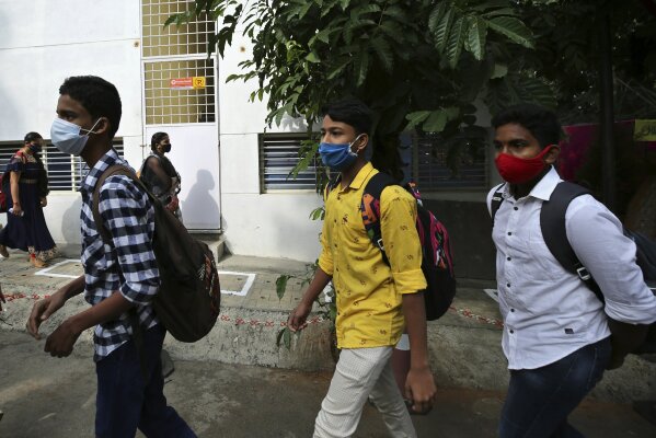 Students wearing face masks as a precaution against the coronavirus arrive to attend classes at a school in Bengaluru, India, Friday, Jan. 1, 2021. The southern state of Karnataka on Friday opened schools for the students of grade 10 and 12 after a gap of more than nine months. India has more than 10 million cases of coronavirus, second behind the United States. (AP Photo/Aijaz Rahi)