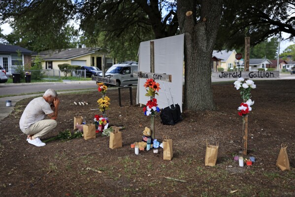 FILE - Will Walsh, of Nocatee, Fla., prays in front of three crosses honoring the victims of Saturday's shooting near the site of the attack at a Dollar General store in Jacksonville, Fla., Monday, Aug. 28, 2023. (Corey Perrine/The Florida Times-Union via AP, File)