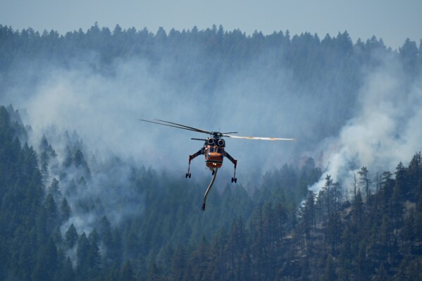 A helicopter looks to make a drop of water as the Quarry wildfire burns in the foothills near the Ken Caryl Ranch development Thursday, Aug. 1, 2024, southwest of Litteton, Colo. (AP Photo/David Zalubowski)