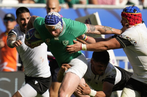 Ireland's Robbie Henshaw, center, is tacked by Romania's Tudor Boldor, right, during the Rugby World Cup Pool B match between Ireland and Romania at the Stade de Bordeaux in Bordeaux, France, Saturday, Sept. 9, 2023. (AP Photo/Themba Hadebe)