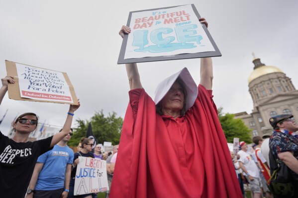 A demonstrator holds a sign during a "No Kings" protest, Saturday, June 14, 2025, in Atlanta. (AP Photo/Mike Stewart)
