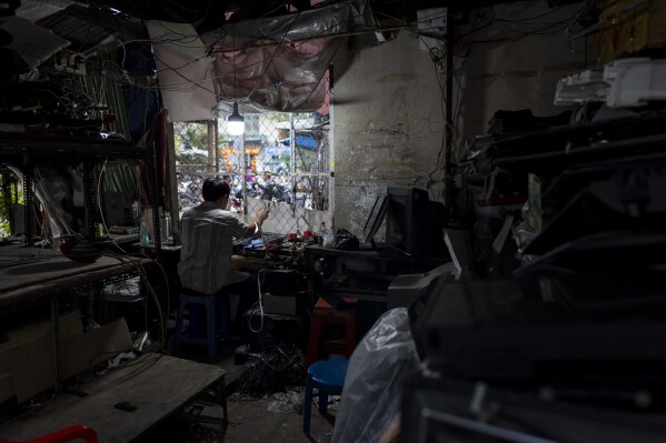 A technician works on an audio device in his repair shop in Nhat Tao market, the largest informal recycling market in Ho Chi Minh City, Vietnam, Sunday, Jan. 28, 2024. (AP Photo/Jae C. Hong)