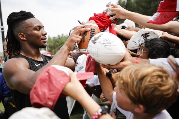 Atlanta Falcons running back Bijan Robinson (7) signs autographs for fans during the NFL football team's training camp, Saturday, July 29, 2023, in Flowery Branch, Ga. (AP Photo/Alex Slitz)