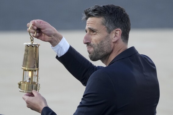Tony Estanguet, President of Paris 2024, holds the Olympic flame during the flame handover ceremony at Panathenaic stadium, where the first modern games were held in 1896, in Athens, Friday, April 26, 2024. On Saturday the flame will board the Belem, a French three-masted sailing ship, built in 1896, to be transported to France. (AP Photo/Petros Giannakouris)