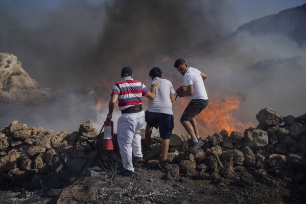 FILE - Local residents try to extinguish a fire, near the seaside resort of Lindos, on the Aegean Sea island of Rhodes, southeastern Greece, on July 24, 2023. Greece’s resort island of Rhodes is nursing its wounds after 11 days of devastating wildfires. (AP Photo/Petros Giannakouris, File)