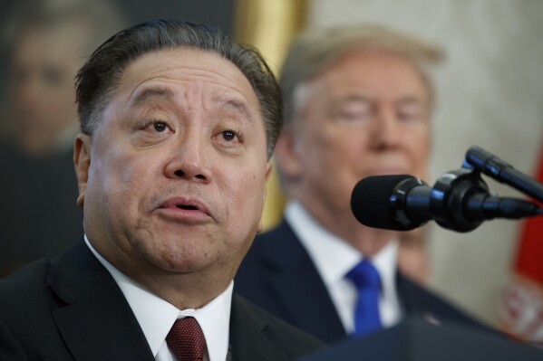 FILE - Broadcom CEO Hock Tan speaks as President Donald Trump listens during an event on Nov. 2, 2017 in Washington.  Tan topped the AP CEO pay survey with a package worth about 2 million in 2023. (AP Photo/Evan Vucci, File)