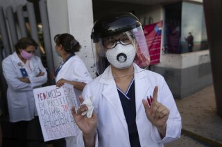 A public hospital worker yells "We want protection!" during a protest outside the hospital where workers demand protective gear and training in Mexico City, Monday, April 13, 2020. Doctors, nurses and other personnel have demonstrated at a number of public hospitals around the country as the new coronavirus sickens medical personnel. (AP Photo/Fernando Llano)