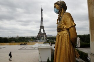 FILE- In this file photo dated Monday, May 4, 2020, a statue wears a mask along Trocadero square close to the Eiffel Tower in Paris.  In a study published Tuesday May 5, 2020, in the International Journal of Microbial Agents, doctors at a hospital north of Paris reviewed retrospective samples of 14 patients treated for atypical pneumonia, and say they may have identified a possible case of the new coronavirus dating back to December 2019. (AP Photo/Christophe Ena, FILE)