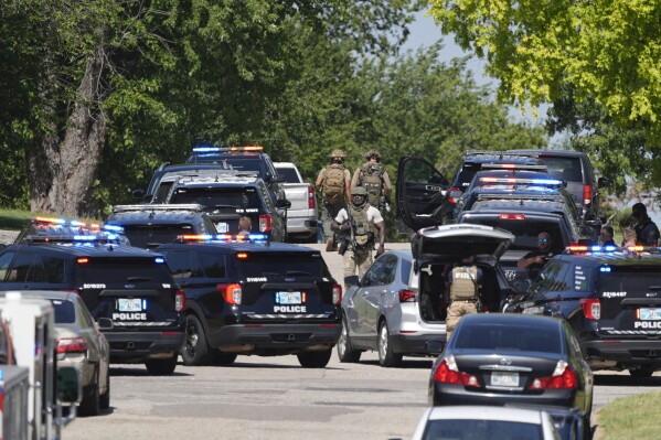 A police presence surrounds West Eubanks Street reports a person was barricaded in a home on Tuesday, July 2, 2024 in Oklahoma City, Okla. A man shot and wounded an Oklahoma City police officer and then barricaded himself inside a home on the city's northwest side. The wounded officer was transported to a hospital, but the extent of his injuries weren't immediately known, said Capt. Valerie Littlejohn. (Sarah Phipps/The Oklahoman via AP)