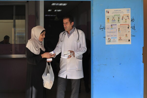 FILE - A Palestinian woman received medicine from a doctor at a clinic run by the agency for Palestinian refugees, or UNRWA, in the Ein el-Hilweh refugee camp in the southern port city of Sidon, Lebanon, Tuesday, June 20, 2023. The U.N. agency for Palestinian refugees says it has decided to suspend all of its services in Lebanon's largest refugee camp as of Friday, Aug. 18, 2023, in protest against the presence of gunmen in its facilities. (AP Photo/Mohammed Zaatari, File)