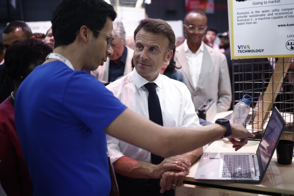 French President Emmanuel Macron discusses with exhibitorsas he visits the Vivatech exhibition in Paris, Wednesday, June 14, 2023. Europe's biggest startup and tech event runs until Sunday June 18, 2023. (Yoan Valat, Pool via AP)