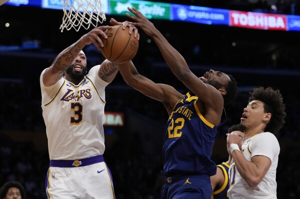 Los Angeles Lakers forward Anthony Davis (3) and Golden State Warriors forward Andrew Wiggins (22) reach for a rebound during the first half of an NBA basketball game in Los Angeles, Saturday, March 16, 2024. (AP Photo/Ashley Landis)