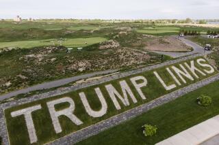 FILE - Patrons play the links as a giant branding sign is displayed with flagstones at Trump Golf Links at Ferry Point in the Bronx borough of New York on Tuesday, May 4, 2021. The Trump Organization sued New York City on Monday, June 21, 2021 for cancelling its contract to run a golf course in the Bronx earlier this year, a move it called ''politically motivated" with no basis in the law that should be reversed. (AP Photo/John Minchillo, File)