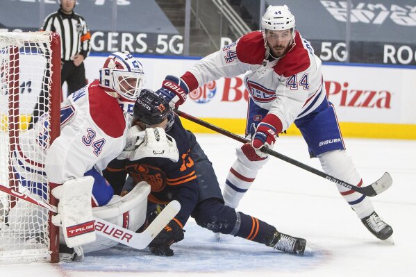 Edmonton Oilers' Jesse Puljujarvi (13) is checked into Montreal Canadiens' goalie Jake Allen (34) by Canadiens' Joel Edmundson (44) during second-period NHL hockey game action in Edmonton, Alberta, Monday, April 19, 2021. (Jason Franson/The Canadian Press via AP)
