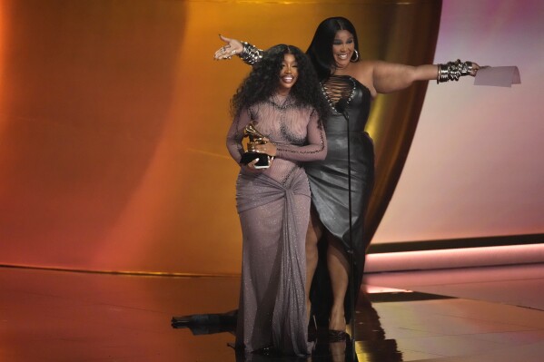 Lizzo, right, presents the award for best R&B song to SZA for "Snooze" during the 66th annual Grammy Awards on Sunday, Feb. 4, 2024, in Los Angeles. (AP Photo/Chris Pizzello)