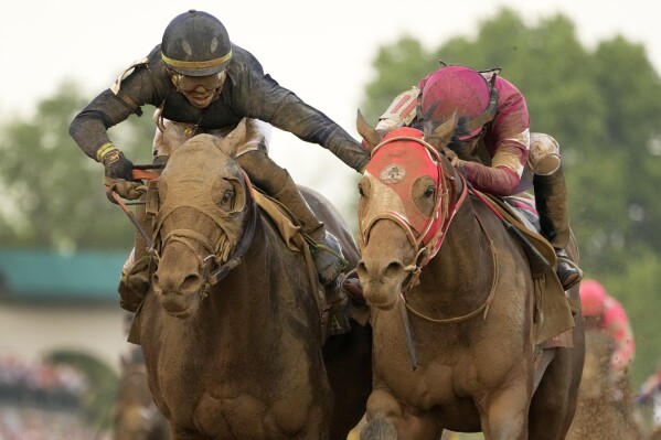 Jockey Tyler Gaffalione riding Sierra Leone, left, reaches toward Ryusei Sakai riding Forever Young as they head to the finish line to finish second and third respectively in the 150th running of the Kentucky Derby horse race at Churchill Downs Saturday, May 4, 2024, in Louisville, Ky. (AP Photo/Jeff Roberson)