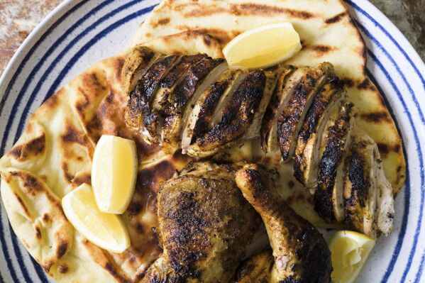 This image released by Milk Street shows a recipe for Iraqi spice-crusted grilled chicken served over warmed flatbread. (Milk Street via AP)