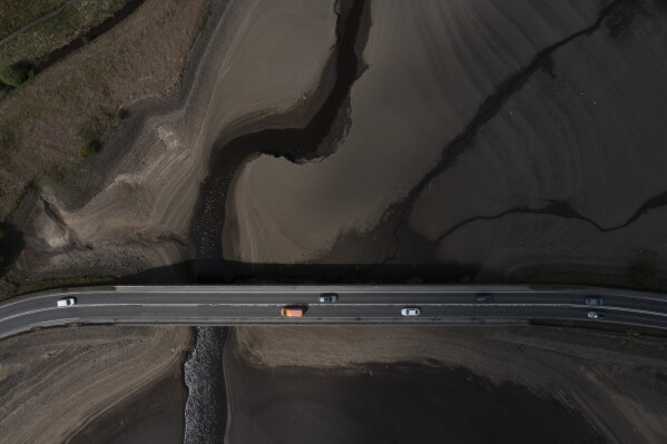 Traffic crosses a bridge at Woodhead Reservoir in Derbyshire as England experiences a significant drought, with reservoir levels at 84% of capacity, lower than the 90% seen in 2022, in Woodhead, England, Monday, May 19, 2025. (AP Photo/Jon Super)