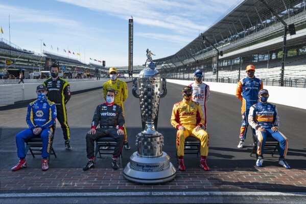 Past winners of the Indianapolis 500 pose with the Borg-Warner Trophy on the start/finish line at Indianapolis Motor Speedway in Indianapolis, Friday, Aug. 21, 2020. They are left to right, front row, Alexander Rossi, Will Power, of Australia, Ryan Hunter-Reay, and Takuma Sato, of Japan. Back row, left to right, Simon Pagenaud, of France, Helio Castroneves, of Brazil, Tony Kanaan, of Brazil, and Scott Dixon, of New Zealand. The 104th running of the Indianapolis 500 auto race is scheduled to run on Sunday.(AP Photo/Michael Conroy)