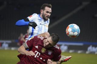 Bayern's Niklas Suele, below, and Berlin's Lucas Tousart battle for the ball during the German Bundesliga soccer match between Hertha Berlin and Bayern Munich at the Olympiastadion in Berlin, Sunday, Jan. 23, 2022. (Soeren Stache/dpa via AP)