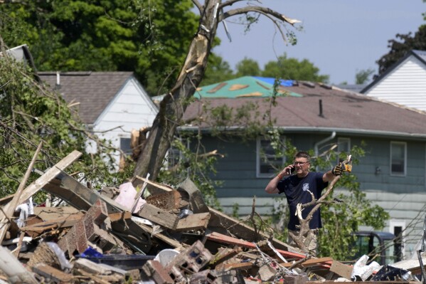 A man talks on his cell phone in front of a tornado damaged home, Wednesday, May 22, 2024, in Greenfield, Iowa. (AP Photo/Charlie Neibergall)