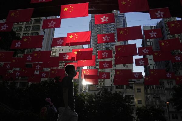 FILE - A man walks past Chinese and Hong Kong flags to celebrate the 25th anniversary of Hong Kong handover to China, in Hong Kong, on June 24, 2022. World Trade Organization arbitrators concluded Wednesday, Dec. 21, 2022, that the United States was out of line in requiring that products from Hong Kong be labeled as “Made in China,” a move that was part of Washington's response to a crackdown on pro-democracy protests there in 2019-2020. (AP Photo/Kin Cheung, File)