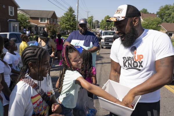 Quientest Vinson, right, of Turn Up Knox hands out candy to children during the Lonsdale Neighborhood Homecoming celebration Saturday, Aug. 5, 2023 in Knoxville, Tenn. (AP Photo/George Walker IV)