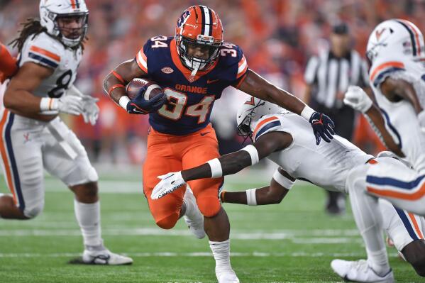 Syracuse running back Sean Tucker (34) tries to break a tackle by Virginia cornerback Anthony Johnson during the first half of an NCAA college football game Friday, Sept. 23, 2022, in Syracuse, N.Y. (AP Photo/Adrian Kraus)