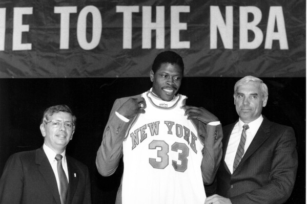 In this June 18, 1985, file photo, Patrick Ewing accepts his New York Knicks jersey from Dave DeBusschere, right, general manager of the Knicks, as NBA commissioner David Stern look on, at the NBA Draft in New York. (AP Photo/Marty Lederhandler, File)
