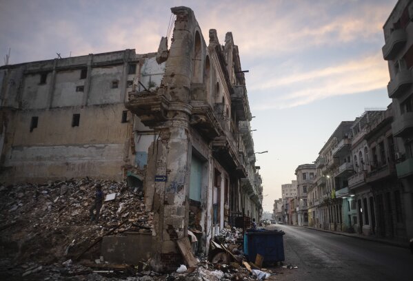 Dilapidated and collapsed buildings line San Lazaro street, where a man, left, collects bricks in downtown Havana, Cuba, Tuesday, Oct. 10, 2023. (AP Photo/Ramon Espinosa)