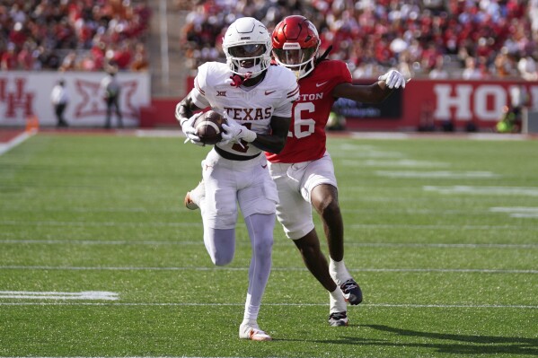 Texas wide receiver Xavier Worthy, left, runs his reception for a touchdown as Houston defensive back Brian George pursues during the first half of an NCAA college football game, Saturday, Oct. 21, 2023, in Houston. (AP Photo/Eric Christian Smith)
