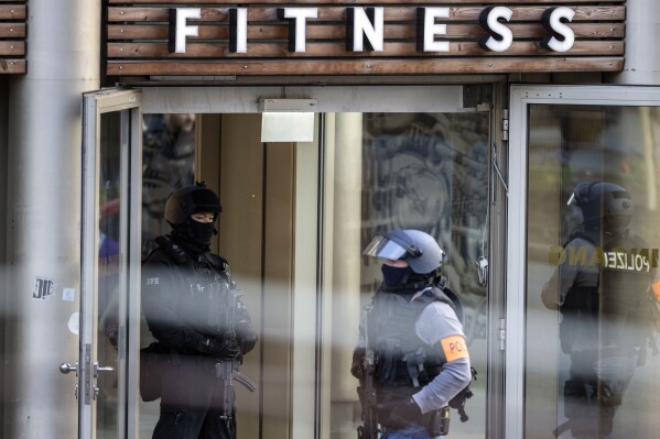 FILE - Armed police officers at the scene of a stabbing attack in a health club in Duisburg, Germany, Tuesday, April 18, 2023. A radicalized Syrian man was convicted of murder, attempted murder and bodily harm on Tuesday, Dec. 19 over two knife attacks in Germany this year, including an assault on visitors to a gym. The 27-year-old defendant, identified only as Maan D. in line with German privacy rules, was sentenced to life in prison. (Christoph Reichwein/dpa via AP)