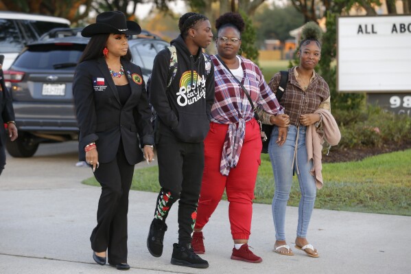 FILE - Candice Matthews, left, National minister of politics for the New Black Panther Nation, Darryl George, center left, and his mother Darresha George, center right, and a unidentified female, right, begin their walk across the street to go into Barbers Hill High School after Darryl served a 5-day in-school suspension for not cutting his hair on Sept. 18, 2023, in Mont Belvieu, Tex. George, 18, a junior has been suspended since Aug. 31. He was told in a letter from the principal on Wednesday, Oct. 11, 2023, that he will be sent to EPIC, an alternative school program from Oct. 12 through Nov. 29 for "failure to comply" with multiple campus and classroom regulations. (AP Photo/Michael Wyke, File)