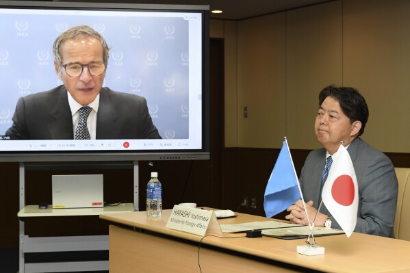 International Atomic Energy Agency Director General Rafael Mariano Grossi, seen on screen, talks with Japanese Foreign Minister Yoshimasa Hayashi, right, during a video conference at the foreign ministry Friday, Aug. 25, 2023, in Tokyo. The tsunami-wrecked Fukushima Daiichi nuclear power plant began releasing its first batch of treated radioactive water into the Pacific Ocean on Thursday — a controversial step that prompted China to ban seafood from Japan.(AP Photo/Norihiro Haruta)