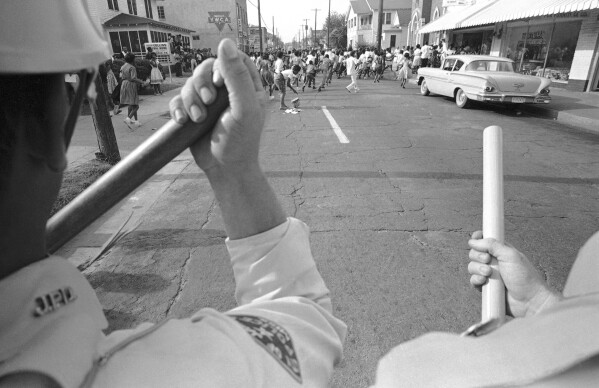 FILE - Faced with a human barricade of Jackson, Miss., police, demonstrators run from scene, May 31, 1963. Friday, May 17, 2024, marks 70 years since the U.S. Supreme Court ruled that separating children in schools by race was unconstitutional. On paper, Brown v. Board of Education still stands. In reality, school integration is all but gone, the victim of a gradual series of court cases that slowly eroded it, leaving little behind. (AP Photo/Jim Bourdier, File)