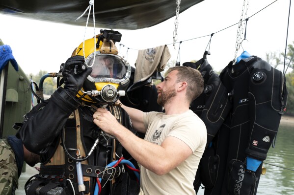 A Belgian military diver is getting ready to dive under the Danube River in Budapest, Hungary, Friday, Oct. 13, 2023, during an international training exercise which prepares military divers to find and remove unexploded underwater ordnances. Hungary this year hosted the 10-day exercise for the second year in a row and provided the soldiers from Hungary, Germany, Belgium and Lithuania with hands-on training in a variety of environments, like facing the powerful current of the Danube River. (AP Photo/Bela Szandelszky)