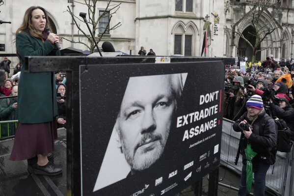 FILE - Stella Assange, wife of Julian Assange, speaks besides a poster of Julian Assange at the Royal Courts of Justice in London, Wednesday, Feb. 21, 2024. A London court is due to rule whether WikiLeaks founder Julian Assange can challenge extradition to the United States on espionage charges. Two judges will issue a ruling Tuesday morning in the High Court on whether Assange can make one final appeal in England. (AP Photo/Kin Cheung, File)