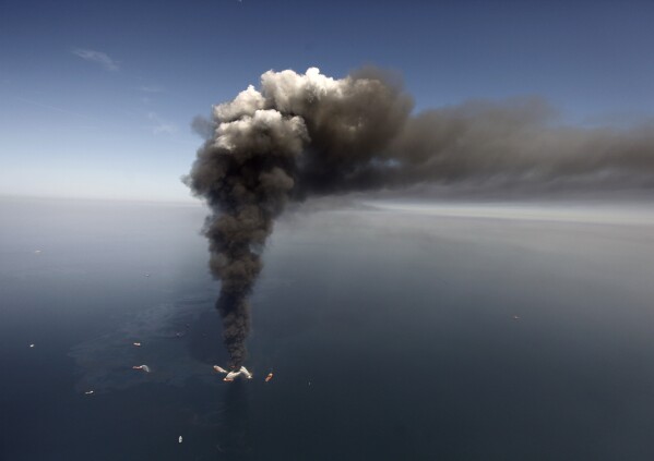 FILE - Oil leaks in the Gulf of Mexico southeast of Venice on Louisiana's tip, as the Deepwater Horizon oil rig burns on April 21, 2010. (AP Photo/Gerald Herbert, File)