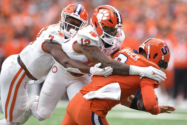 Clemson defensive ends Justin Mascoll, left, and T.J. Parker sack Syracuse quarterback Garrett Shrader during the first half of an NCAA college football game in Syracuse, N.Y., Saturday, Sept. 30, 2023. (AP Photo/Adrian Kraus)