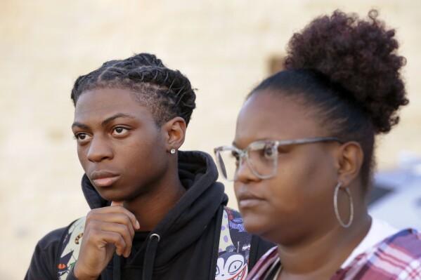 FILE - Darryl George, left, an 18 year-old junior, and his mother Darresha George, right, talk with reporters before walking into Barbers Hill High School after he served an in-school suspension for not cutting his hair on Sept. 18, 2023, in Mont Belvieu, Texas. Darryl George will be sent to EPIC, an alternative school program, from Oct. 12 through Nov. 29 for “failure to comply” with multiple campus and classroom regulations, the principal said in a Wednesday, Oct. 11, letter provided to The Associated Press by the family. (AP Photo/Michael Wyke, File)