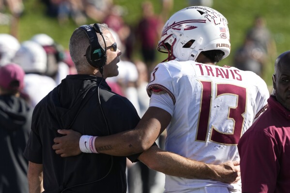 Florida State head coach Mike Norvell, left, talks with quarterback Jordan Travis (13) during the second half of an NCAA college football game against Wake Forest in Winston-Salem, N.C., Saturday, Oct. 28, 2023. (AP Photo/Chuck Burton)