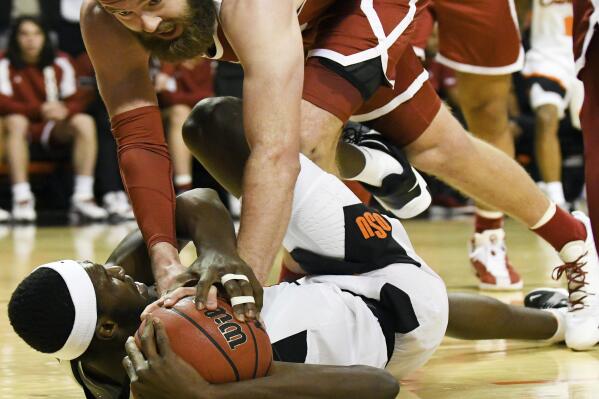 Oklahoma forward Tanner Groves (35) reaches for the ball being held by Oklahoma State forward Moussa Cisse (33) in the first half of an NCAA college basketball game Saturday, Feb. 5, 2022, in Stillwater, Okla. (AP Photo/Brody Schmidt)
