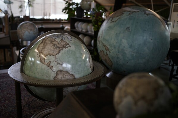 Various size of globes are displayed at a studio in London, Tuesday, Feb. 27, 2024. Globes in the age of Google Earth capture the imagination and serve as snapshots of how the owners see the world and their place in it. Peter Bellerby made his first globe for his father, after he could not find one accurate or attractive enough. In 2008, he founded Bellerby & Co. Globemakers in London. His team of dozens of artists and cartographers has made thousands of bespoke globes up to 50 inches in diameter. The most ornate can cost six figures. (AP Photo/Kin Cheung)