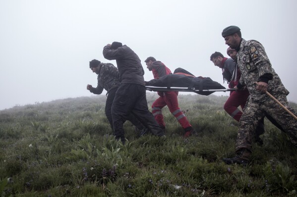 In this photo provided by Moj News Agency, rescue teams members carry the body of a victim after a helicopter carrying Iranian President Ebrahim Raisi crashed in Varzaghan, northwestern Iran, Monday, May 20, 2024. Iranian President Ebrahim Raisi, the country’s foreign minister and others have been found dead at the site of a helicopter crash after an hours-long search through a foggy, mountainous region of the country’s northwest, state media reported. (Azin Haghighi, Moj News Agency via AP)