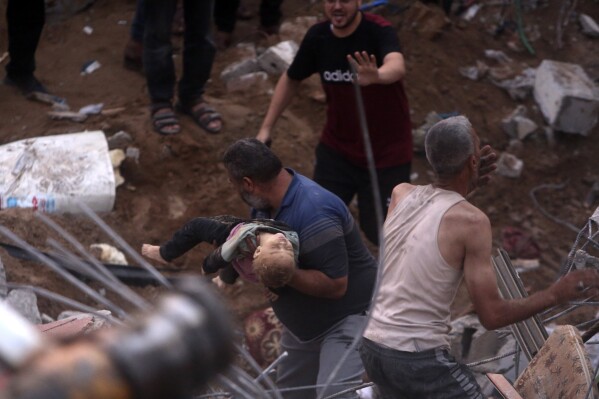 EDS NOTE: GRAPHIC CONTENT - Palestinians carry a dead child who was found under the rubble of a destroyed building following Israeli airstrikes in Nusseirat refugee camp, central Gaza Strip, Tuesday, Oct. 31, 2023. (AP Photo/Mohammed Dahman)