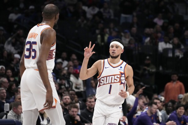 Phoenix Suns guard Devin Booker (1) celebrates after sinking a three-point basket as Kevin Durant (35) looks on in the second half of an NBA basketball game against the Dallas Mavericks in Dallas, Wednesday, Jan. 24, 2024. (AP Photo/Tony Gutierrez)